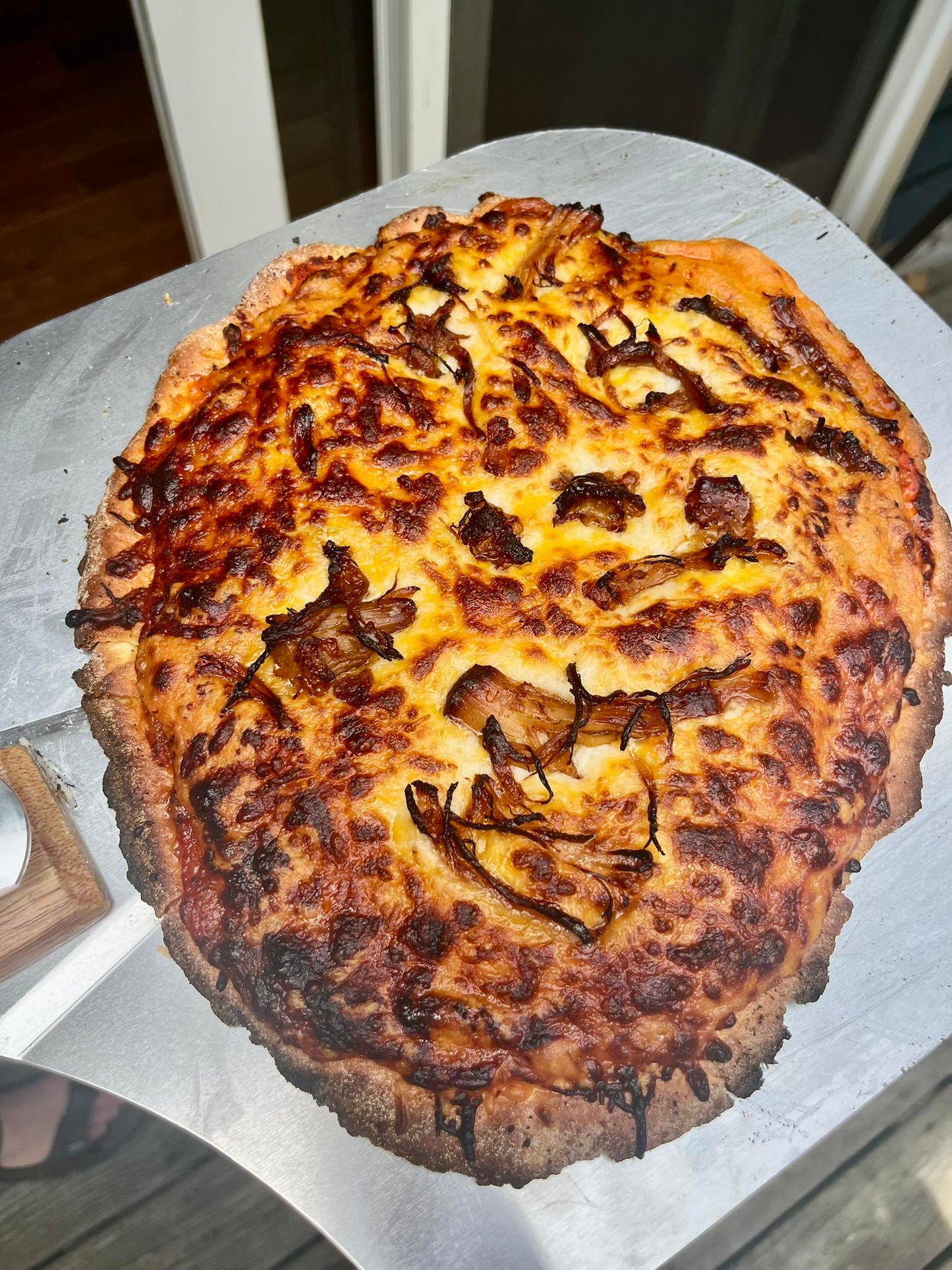 Cheesy pizza with a charred crust on a white surface