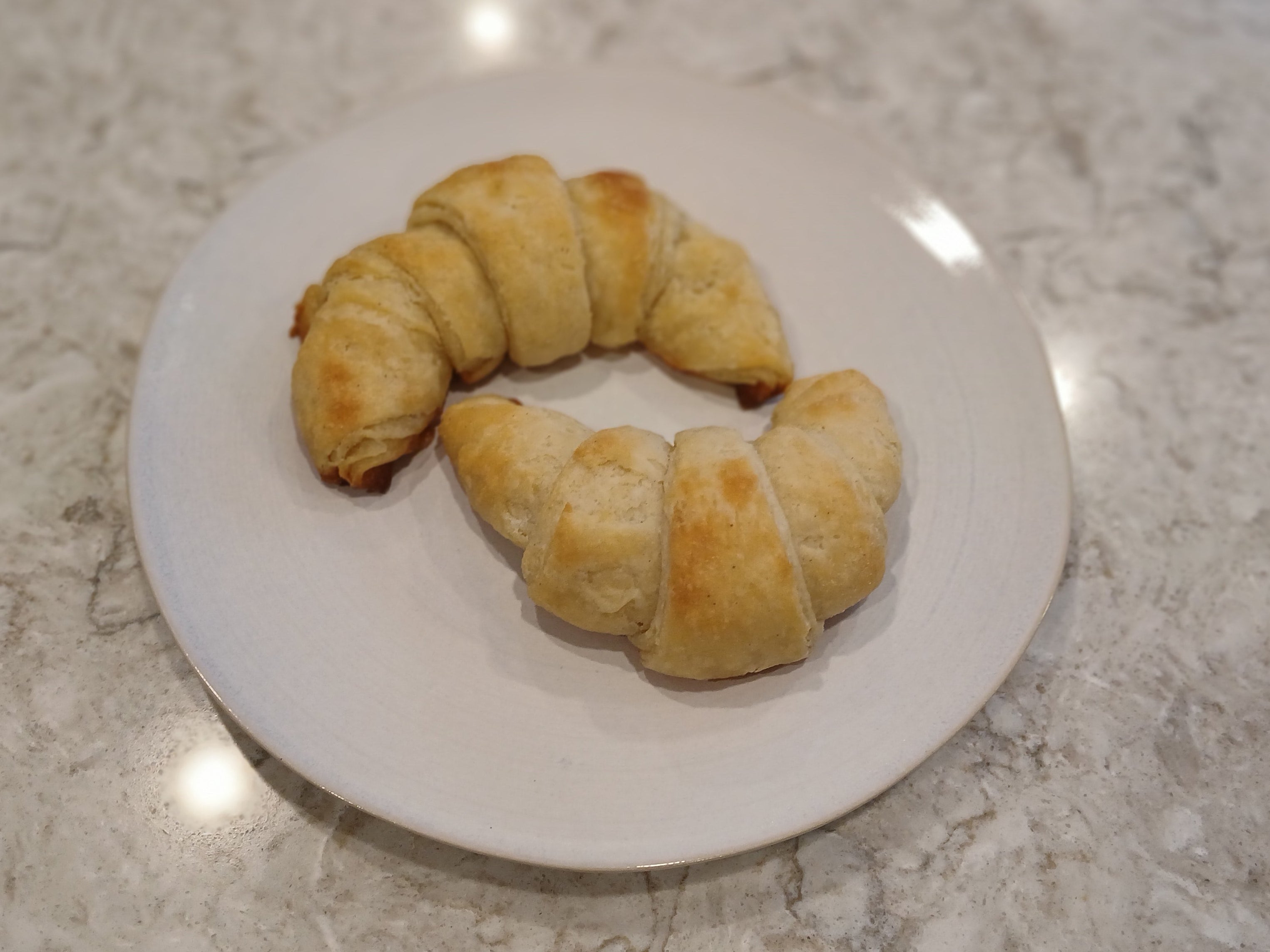 Gluten-free Croissants on a white plate on a marble countertop