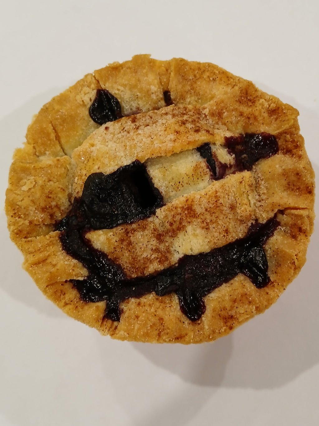 Gluten Free Blueberry pie on a white plate with a wooden surface underneath