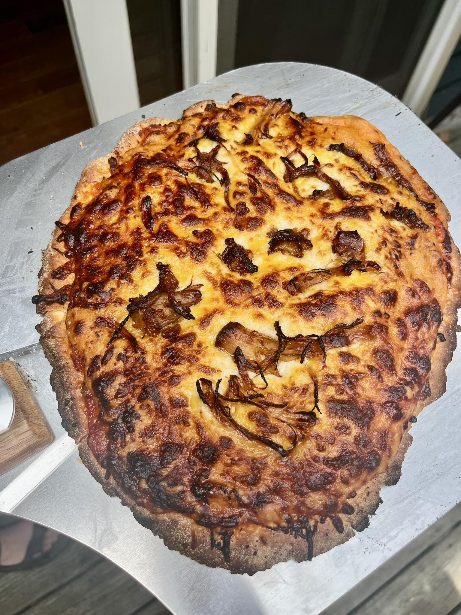 Cheesy pizza with a charred crust on a white surface