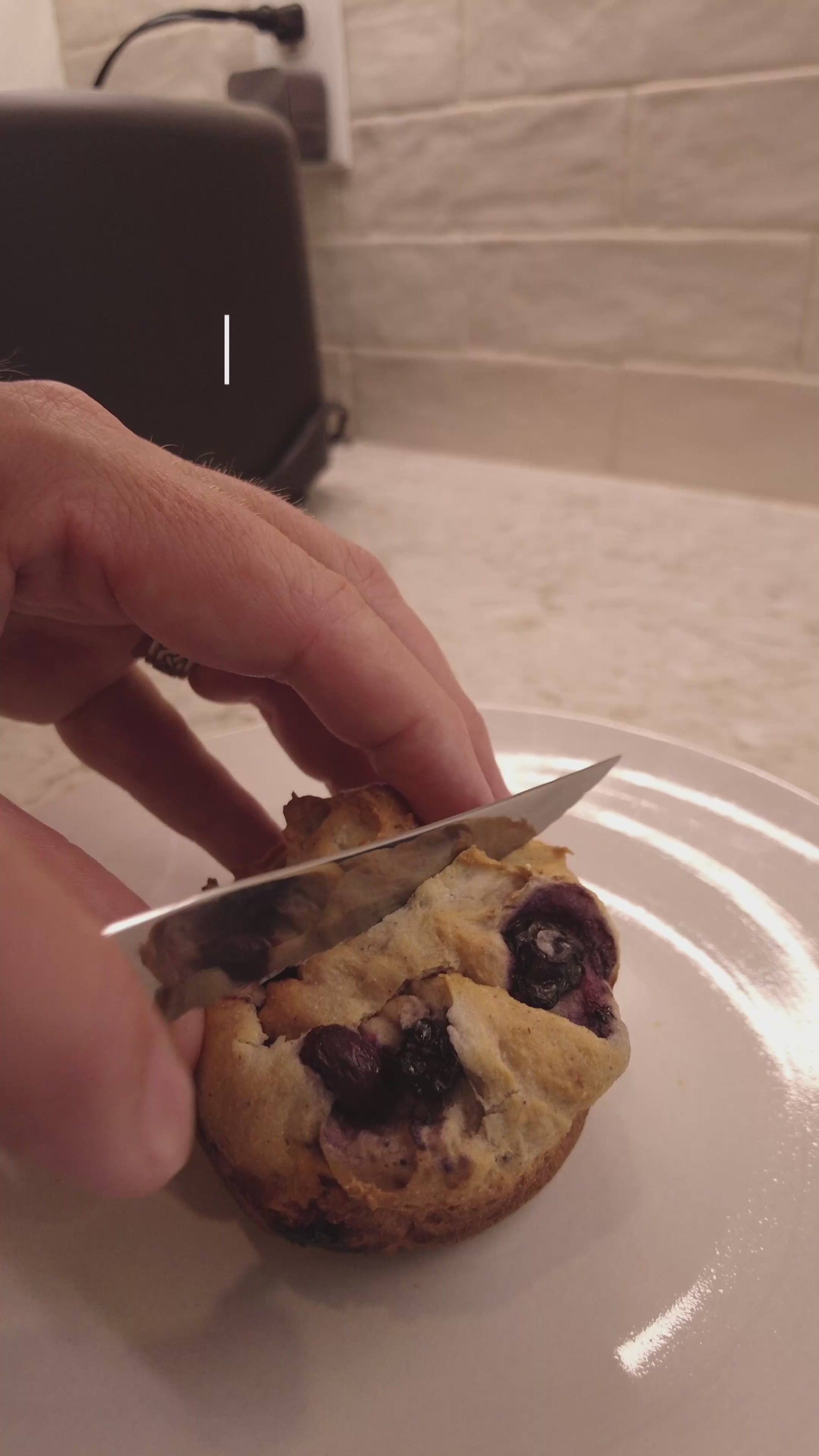 Cutting a gluten free blueberry muffin on a plate